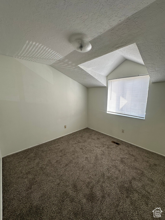 Bonus room featuring a textured ceiling, visible vents, vaulted ceiling, carpet floors, and baseboards