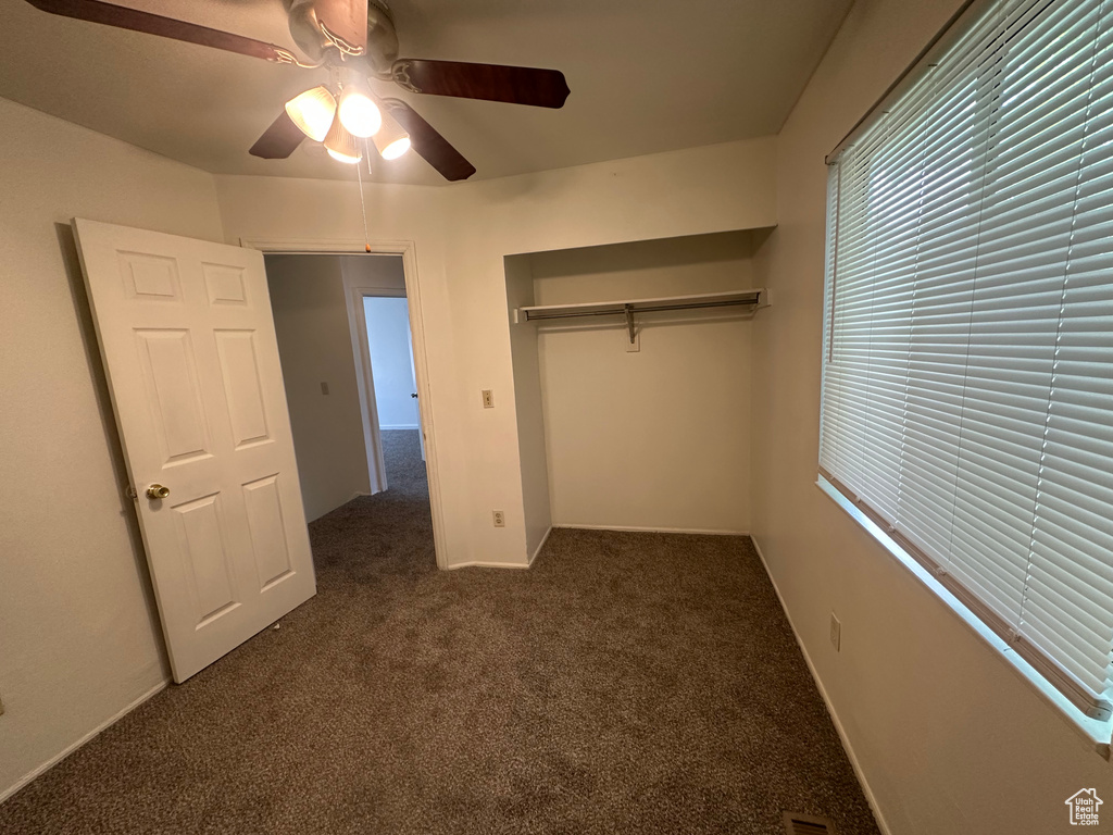 Unfurnished bedroom featuring a closet, carpet flooring, baseboards, and a ceiling fan