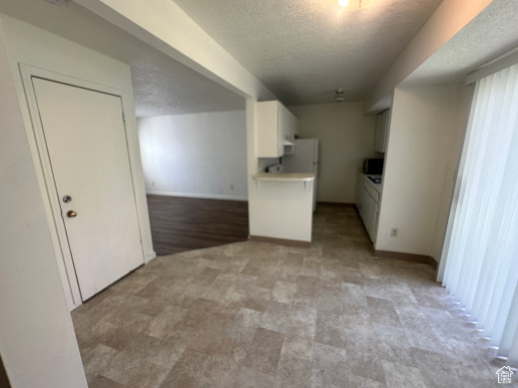 Interior space featuring a textured ceiling and light colored carpet