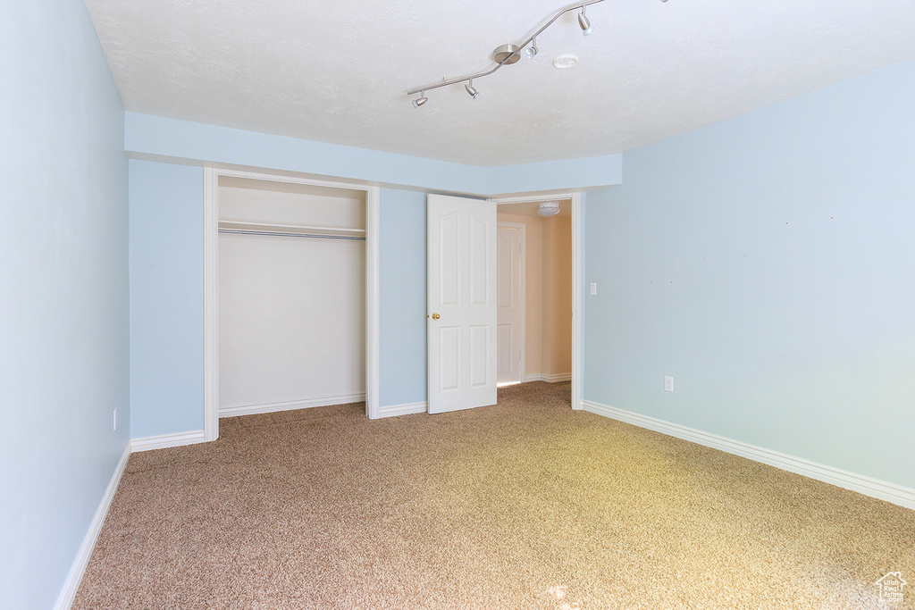 Unfurnished bedroom featuring baseboards, light colored carpet, and a closet