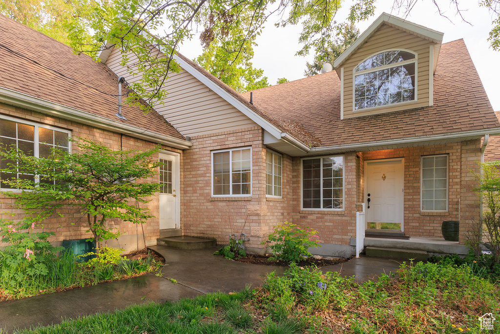 View of front of house featuring roof with shingles and brick siding