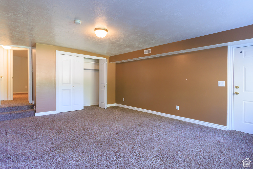 Unfurnished bedroom with baseboards, carpet, a closet, and visible vents