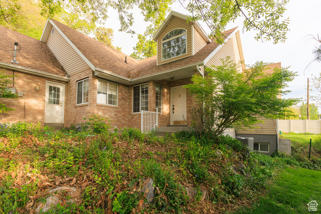 Exterior space with brick siding, fence, and roof with shingles