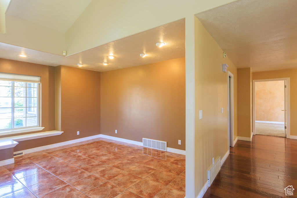 Spare room featuring visible vents, baseboards, and vaulted ceiling