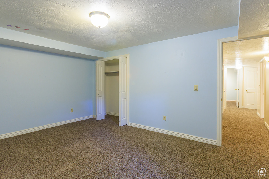 Unfurnished bedroom with carpet floors, a textured ceiling, and baseboards