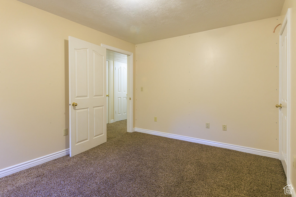 Unfurnished bedroom featuring baseboards, carpet, and a textured ceiling