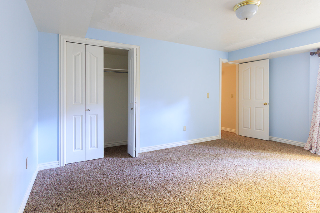Unfurnished bedroom featuring carpet flooring, baseboards, and a closet