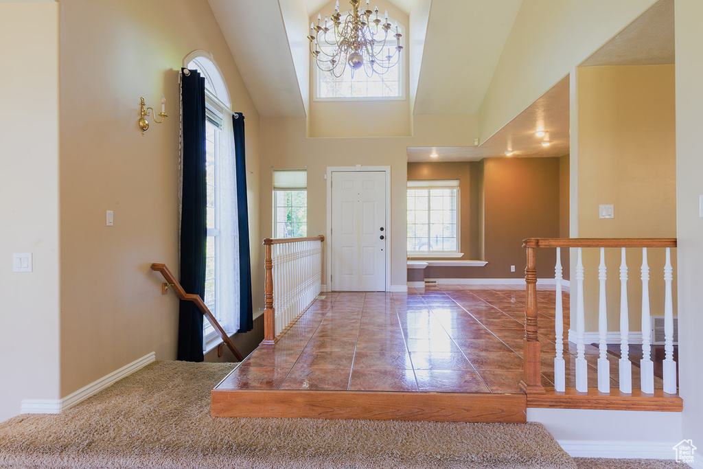 Foyer entrance with baseboards, a chandelier, a high ceiling, and marble finish floor