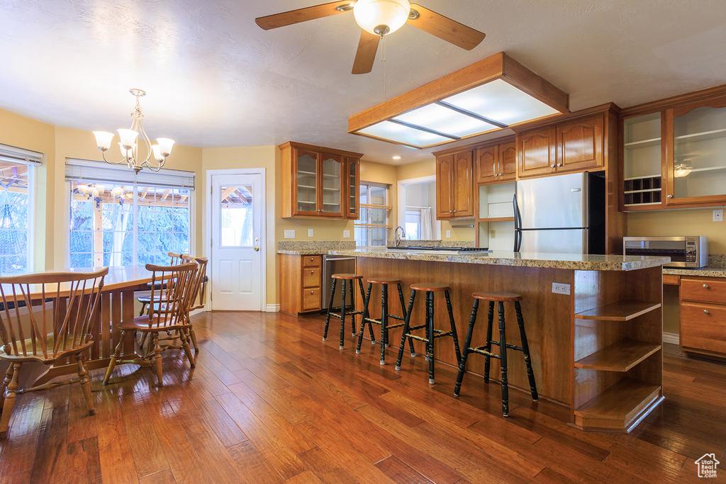Kitchen with dark wood-type flooring, open shelves, brown cabinets, and stainless steel appliances