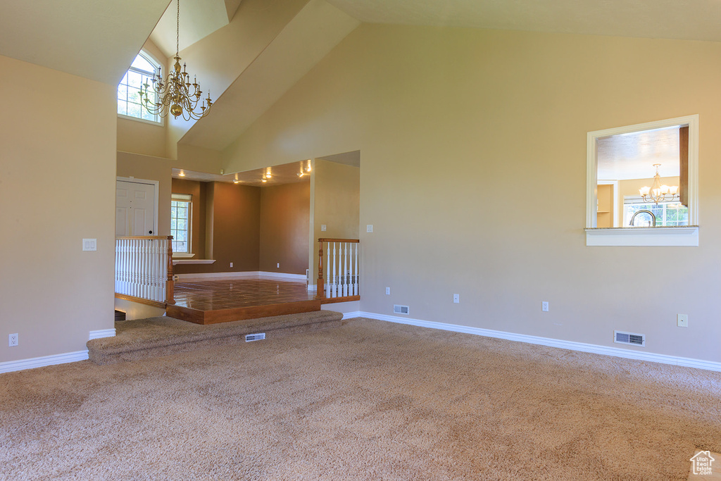 Unfurnished room featuring carpet flooring, high vaulted ceiling, a chandelier, and visible vents