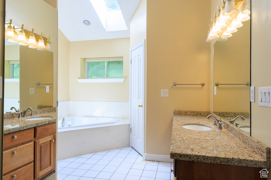 Full bathroom with a skylight, tile patterned flooring, a sink, and two vanities