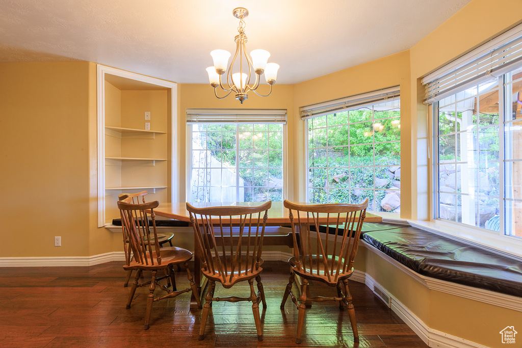 Dining space featuring baseboards, a notable chandelier, and hardwood / wood-style flooring