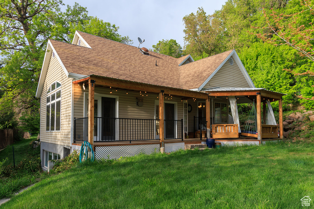 Rear view of house with roof with shingles and a lawn