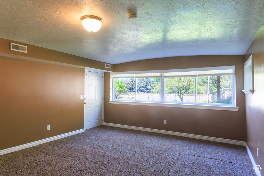 Unfurnished room with visible vents, a textured ceiling, carpet, and baseboards