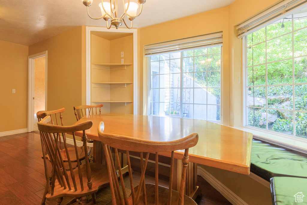 Dining room with wood finished floors, baseboards, a chandelier, and a healthy amount of sunlight