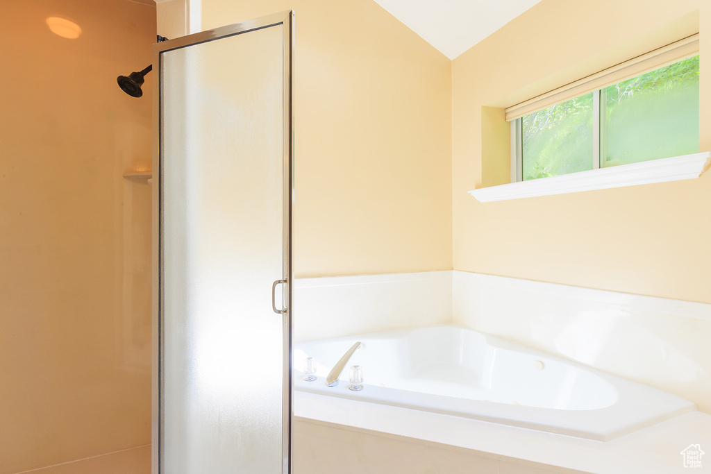 Bathroom with vaulted ceiling, a bath, and a stall shower
