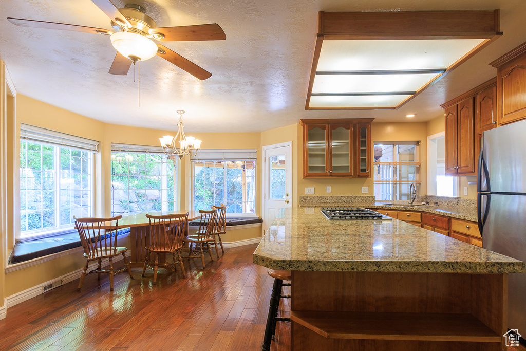 Kitchen featuring brown cabinetry, dark wood-style flooring, glass insert cabinets, baseboards, and appliances with stainless steel finishes