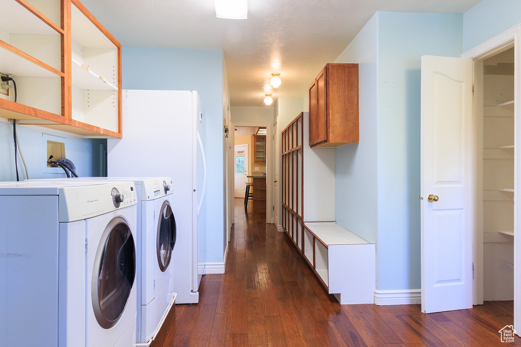 Laundry area with baseboards, washer and clothes dryer, and dark wood finished floors