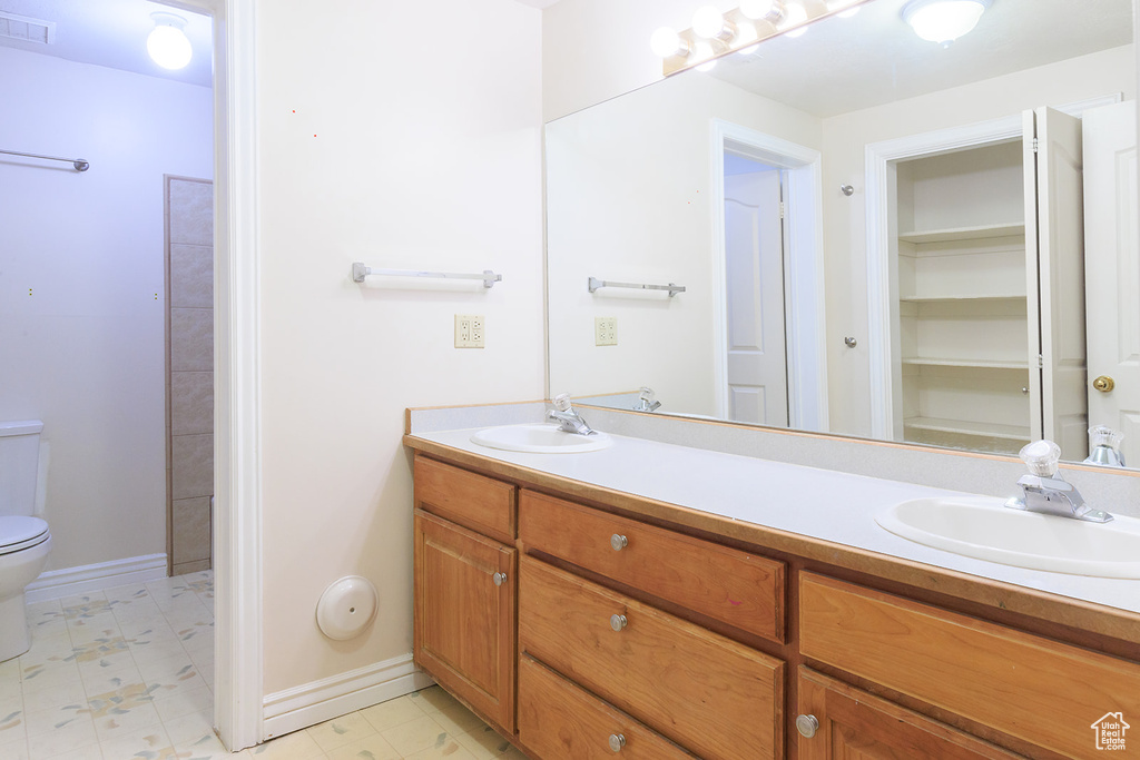Bathroom with a sink, toilet, double vanity, and visible vents