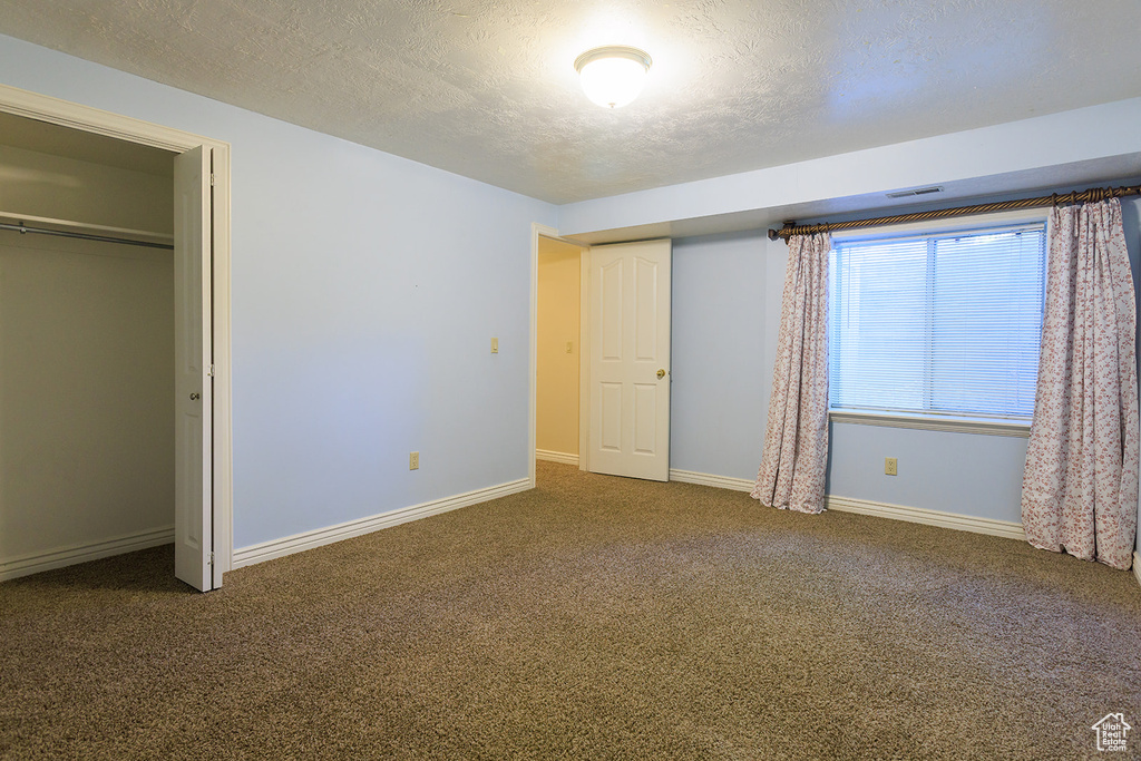 Unfurnished bedroom with baseboards, carpet flooring, a textured ceiling, and visible vents