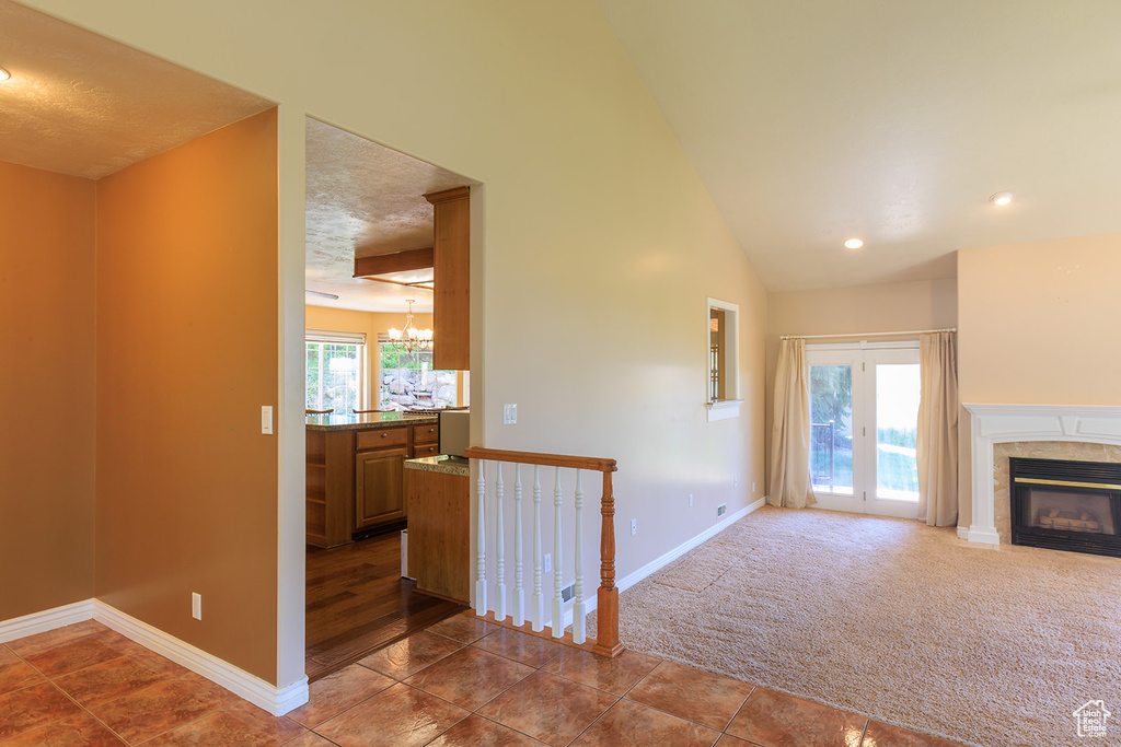 Unfurnished living room with baseboards, a high end fireplace, dark tile patterned floors, and a notable chandelier