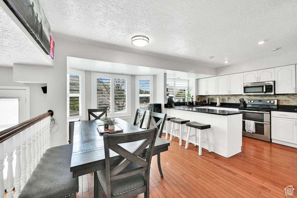 Dining room featuring light wood-style flooring, recessed lighting, and a textured ceiling