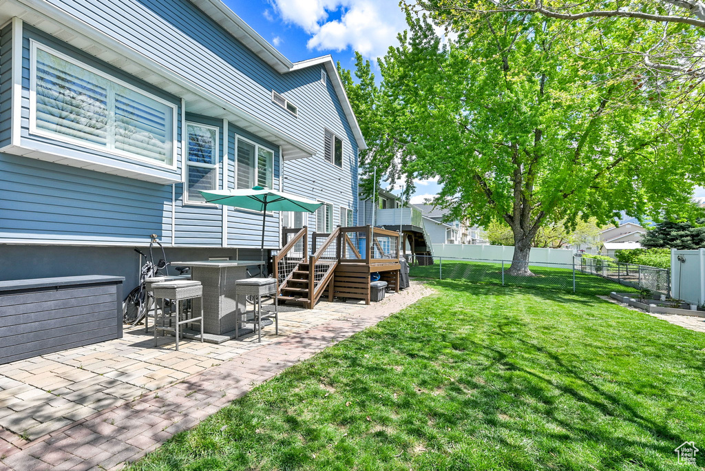 View of yard featuring fence, a wooden deck, and a patio