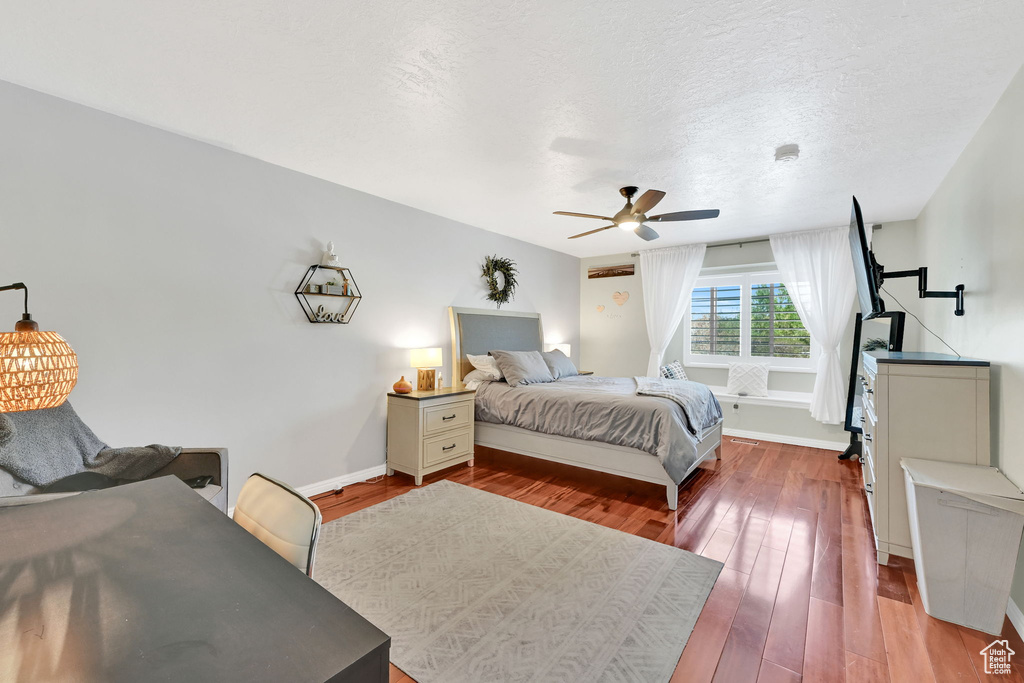 Bedroom featuring baseboards, a ceiling fan, dark wood-style flooring, and a textured ceiling