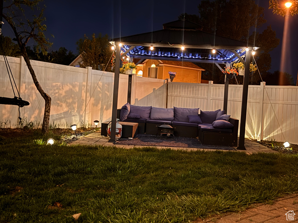 Yard at night with outdoor lounge area, a fenced backyard, and a patio area