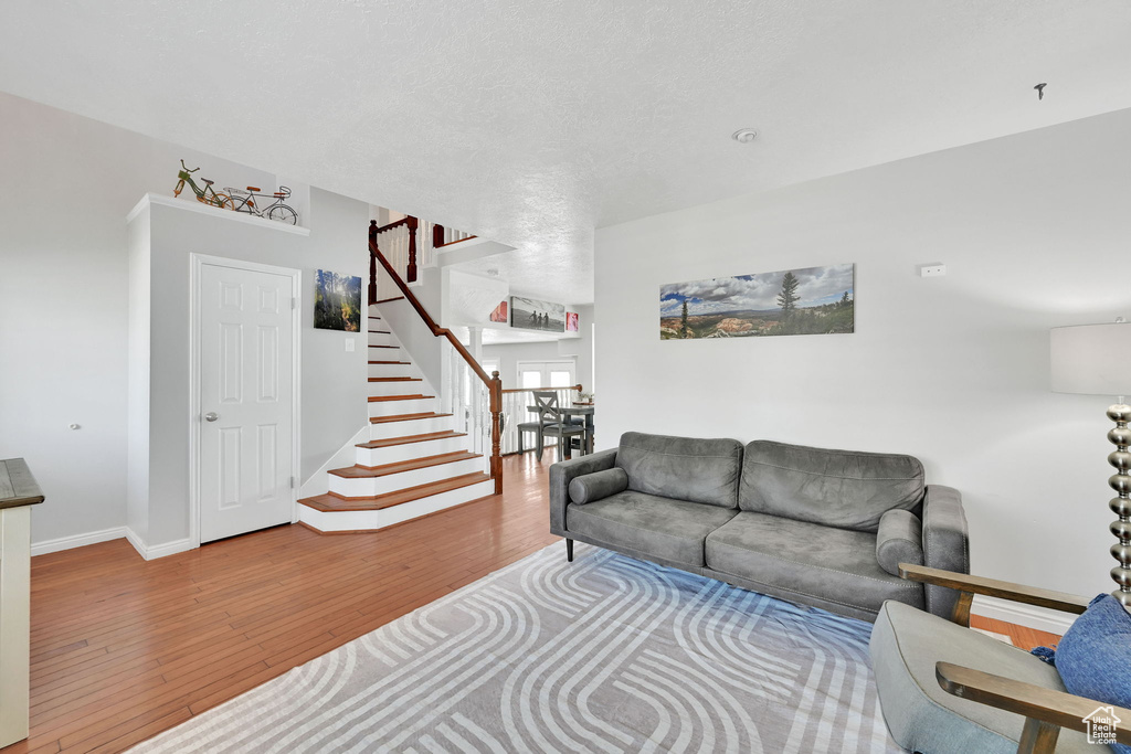 Living area with baseboards, stairs, and wood finished floors