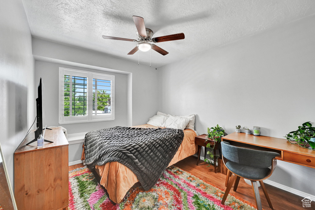 Bedroom with baseboards, a ceiling fan, a textured ceiling, and wood finished floors