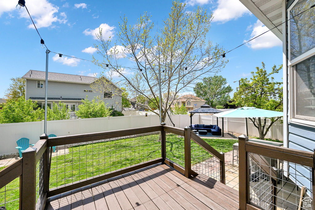 Wooden deck with a gazebo, a fenced backyard, outdoor lounge area, and a yard