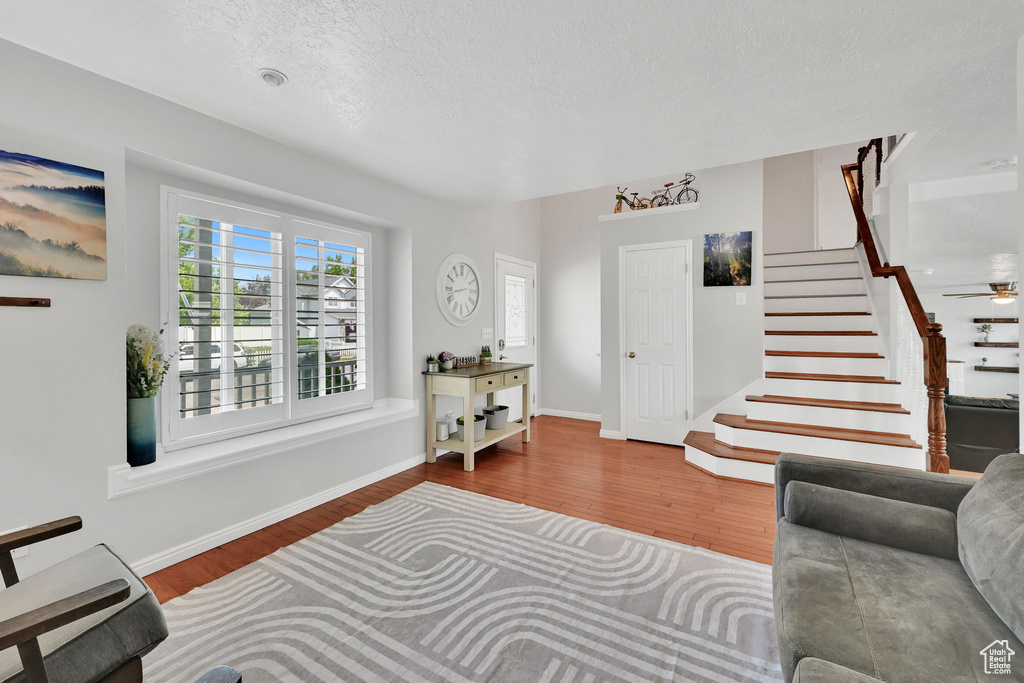 Living area featuring baseboards, a textured ceiling, wood finished floors, and stairway