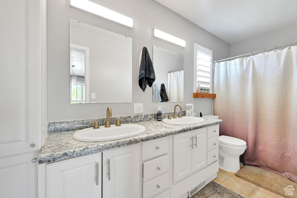 Bathroom with double vanity, a healthy amount of sunlight, and a sink