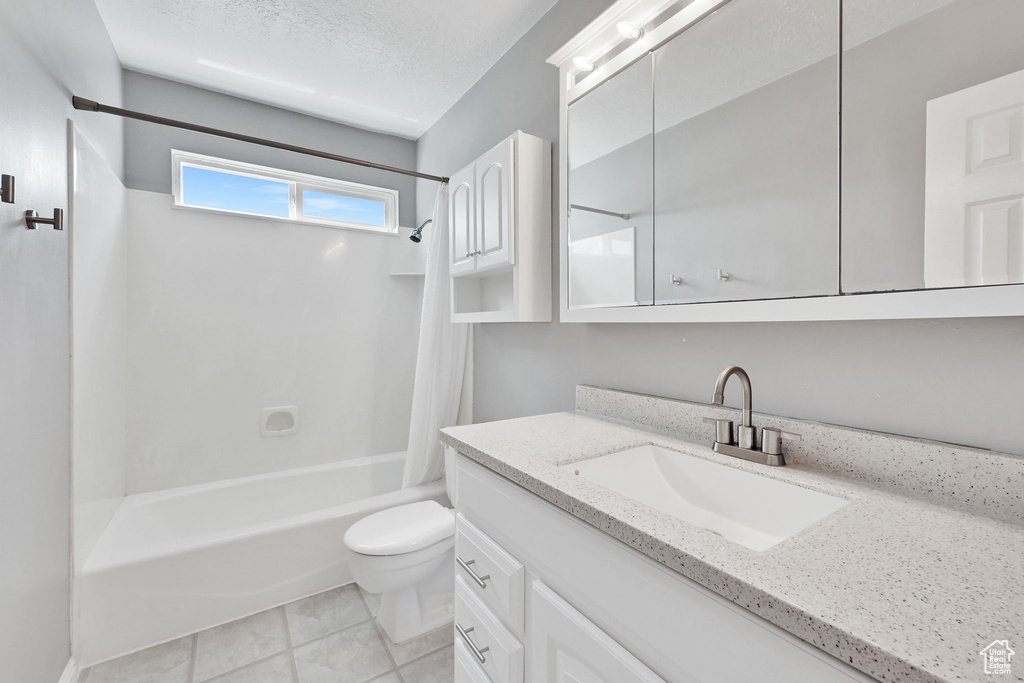 Bathroom with vanity, tile patterned floors, shower / bath combo, and toilet