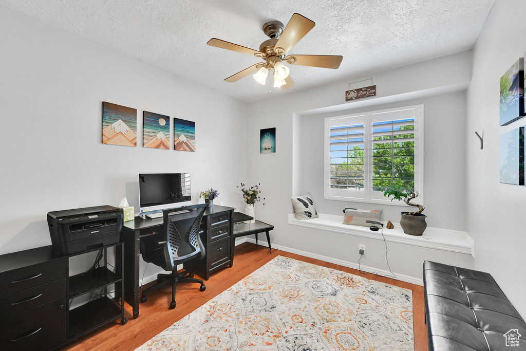 Office space featuring baseboards, a textured ceiling, ceiling fan, and wood finished floors