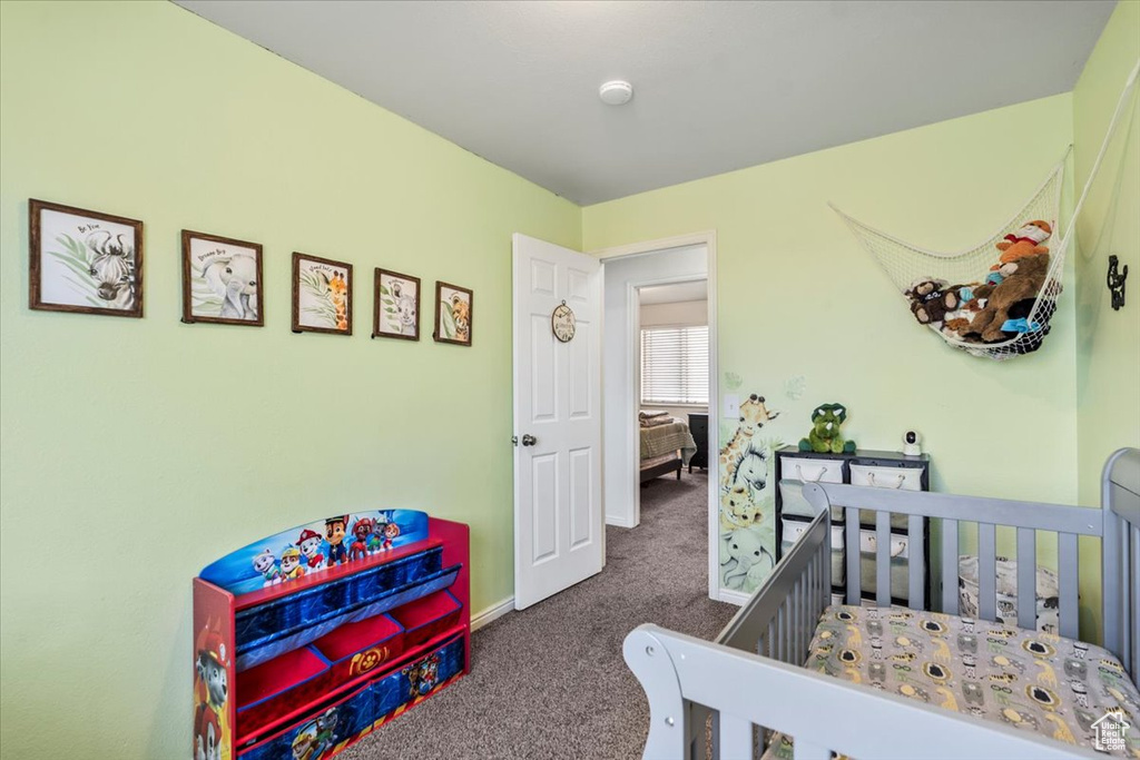 Carpeted bedroom featuring baseboards and a crib