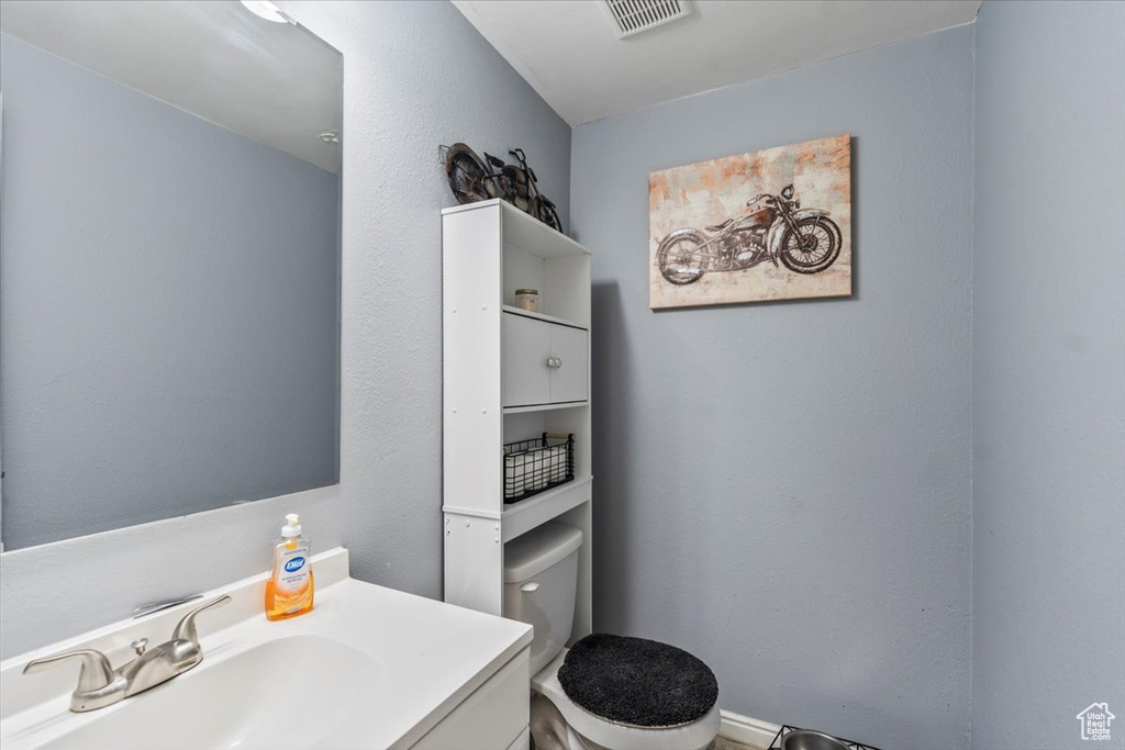Bathroom featuring visible vents, toilet, and vanity