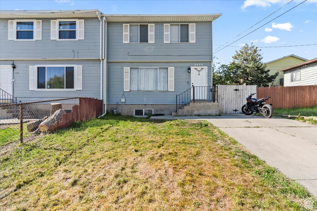 Rear view of house featuring a lawn and fence