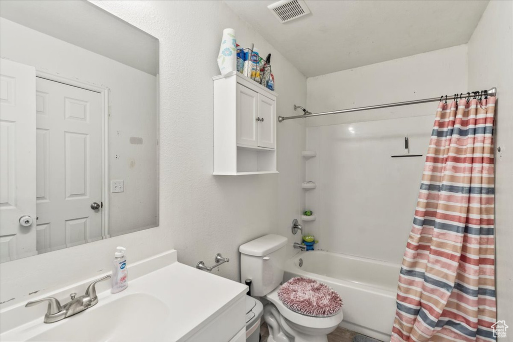 Bathroom with shower / tub combo, vanity, toilet, and visible vents