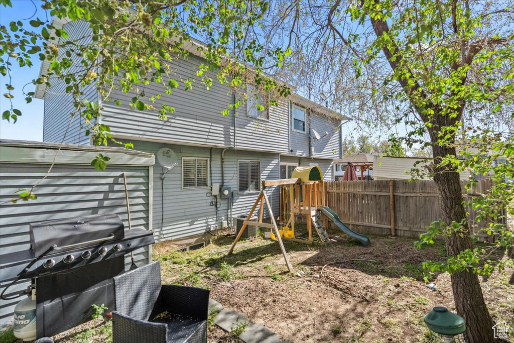 Rear view of property featuring fence and a playground