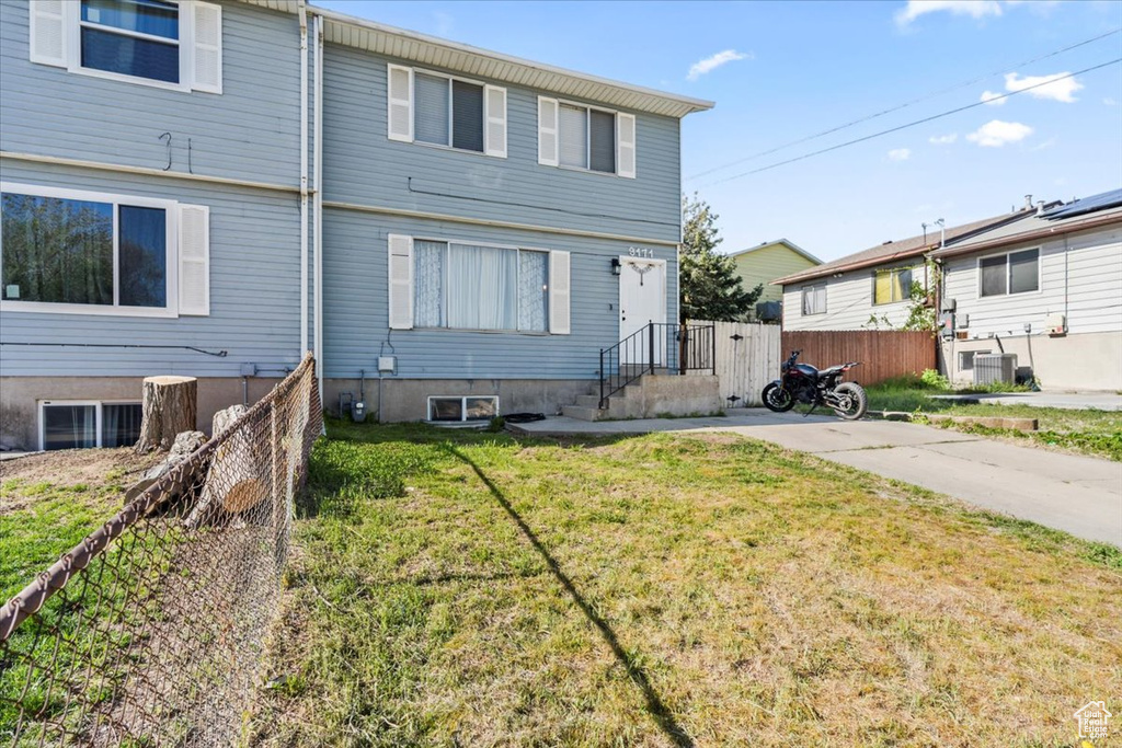 View of front of property with central air condition unit, fence, and a front yard