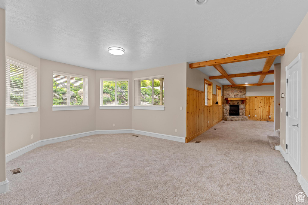 Unfurnished living room featuring wooden walls, a healthy amount of sunlight, carpet, and a fireplace
