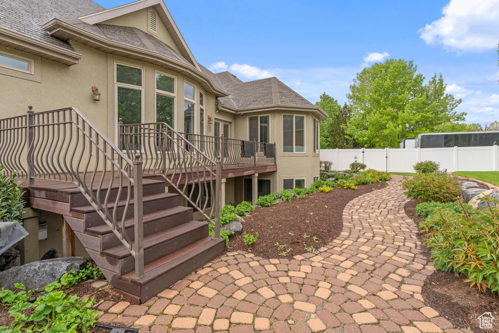 Back of property featuring a deck, fence, stairs, and stucco siding