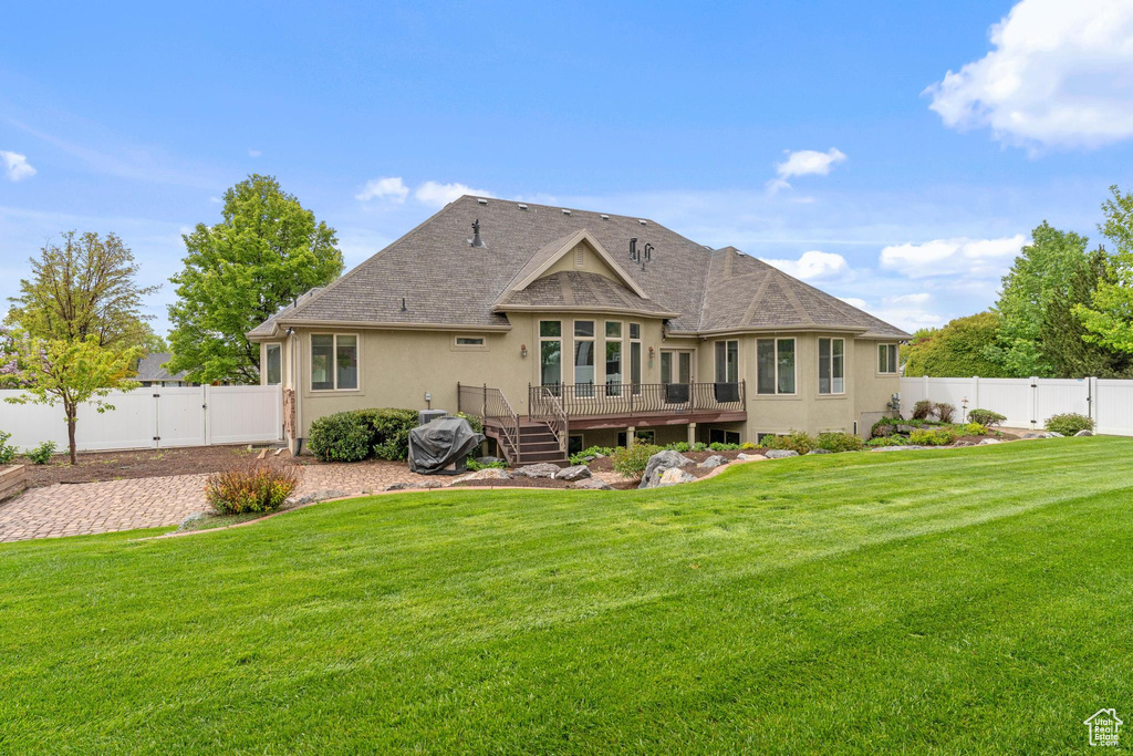 Rear view of house featuring a deck, a gate, a fenced backyard, a yard, and stucco siding