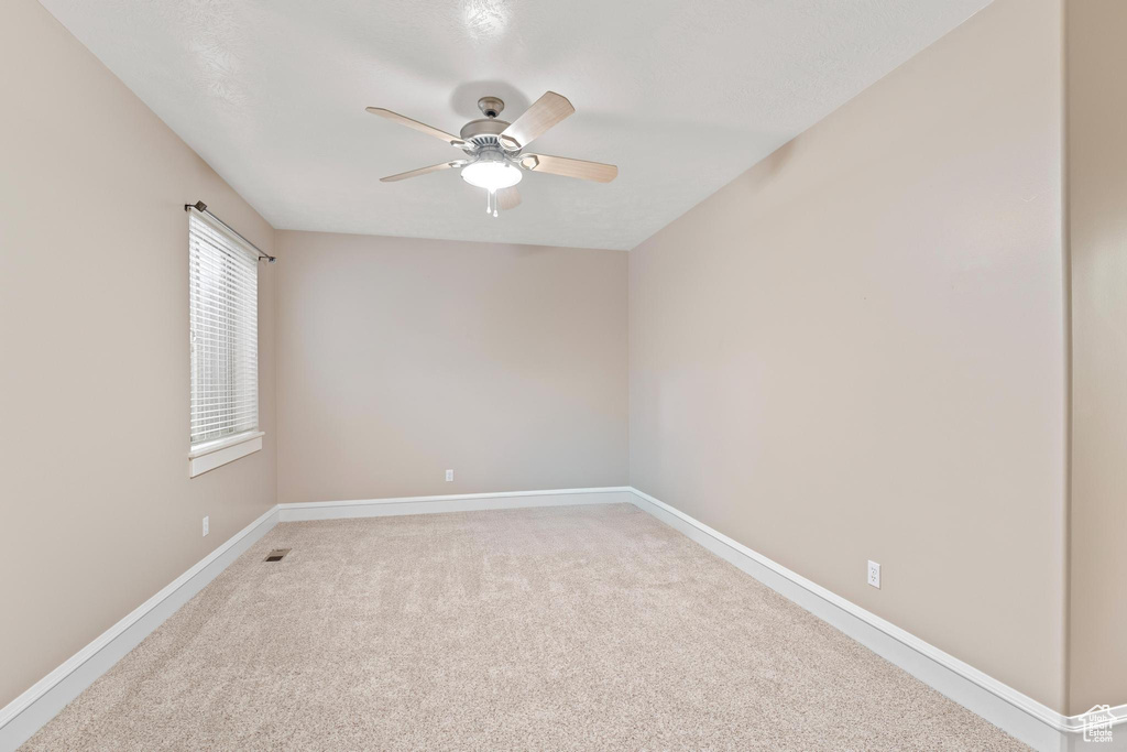 Spare room with light colored carpet, a ceiling fan, and baseboards
