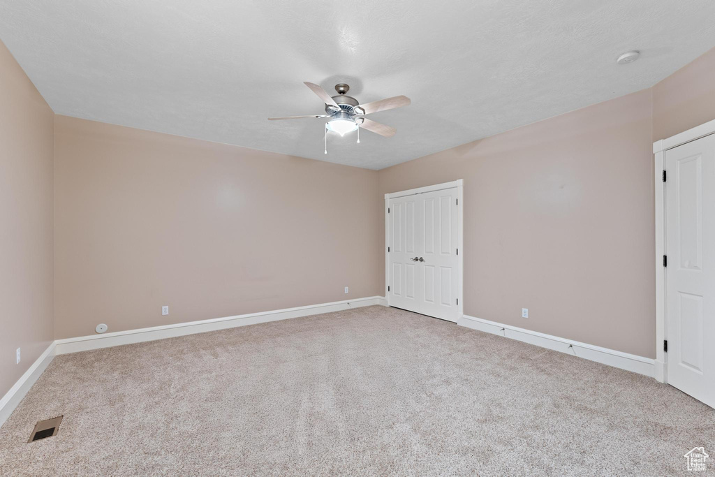 Carpeted empty room with visible vents, baseboards, and ceiling fan