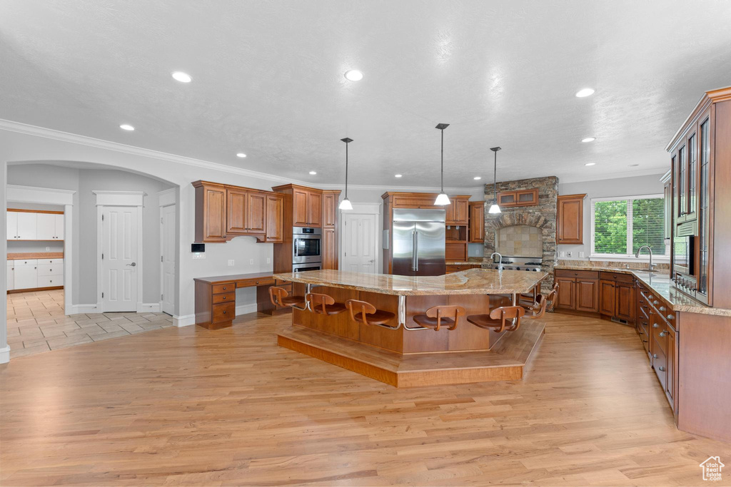 Kitchen featuring brown cabinets, stainless steel appliances, a spacious island, and light wood-type flooring