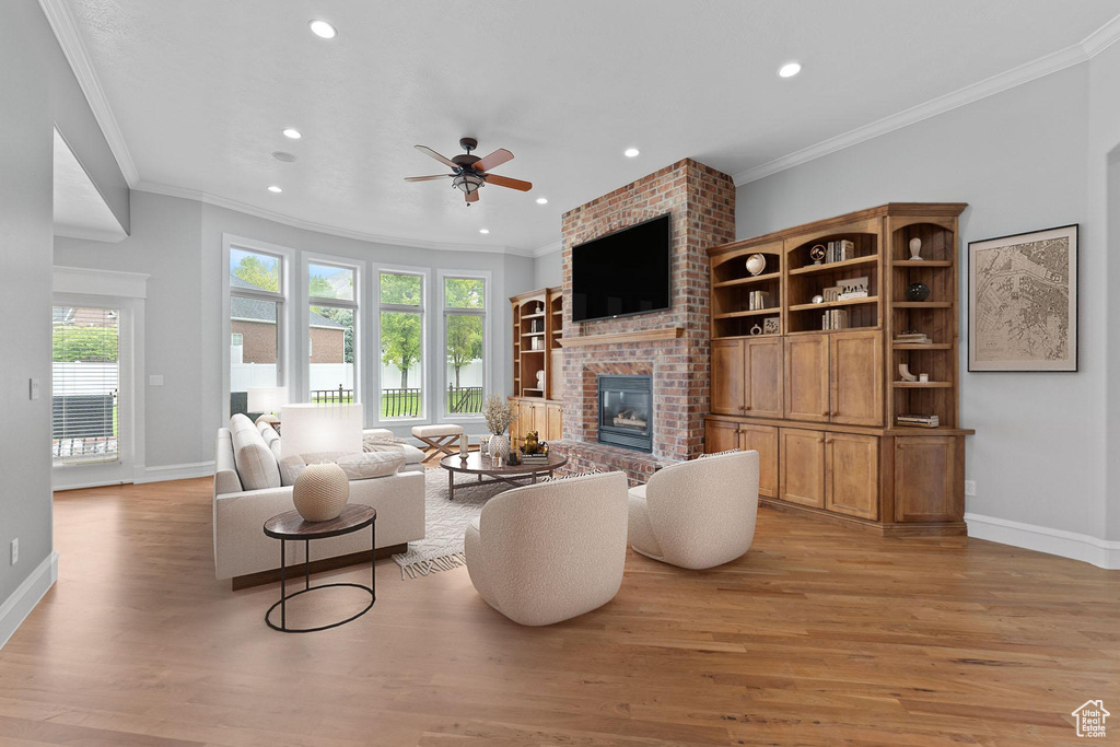 Living room featuring healthy amount of natural light, a fireplace, recessed lighting, a ceiling fan, and light wood-style flooring