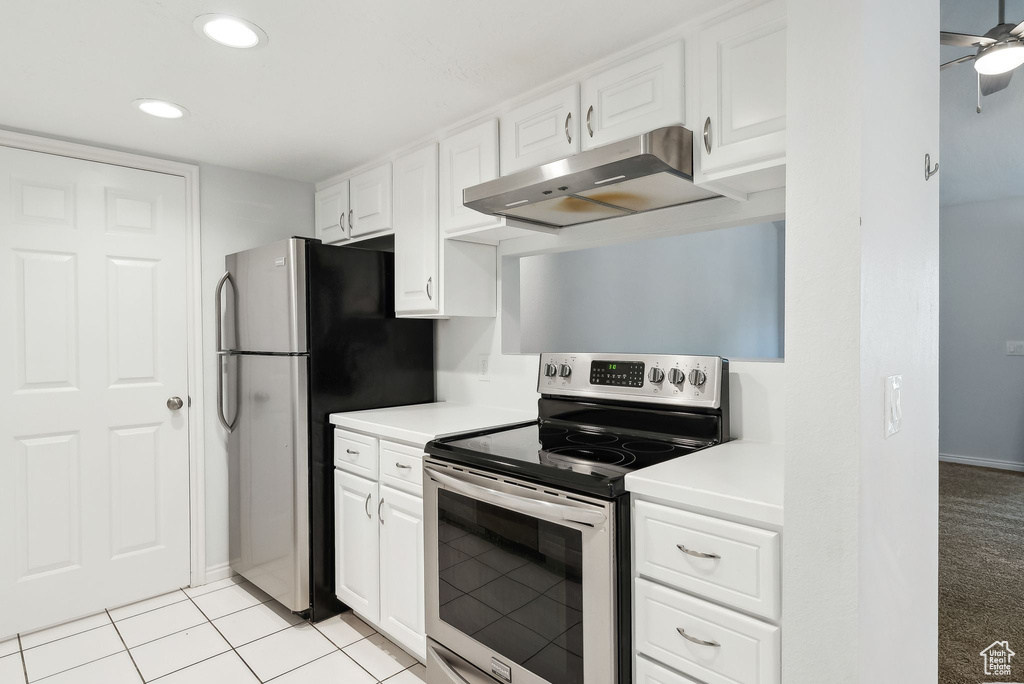 Kitchen with under cabinet range hood, stainless steel appliances, white cabinetry, and light countertops